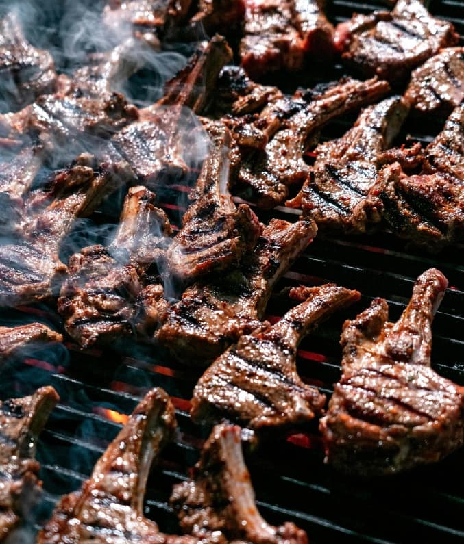 Lamb chops sizzling on a smoky charcoal grill